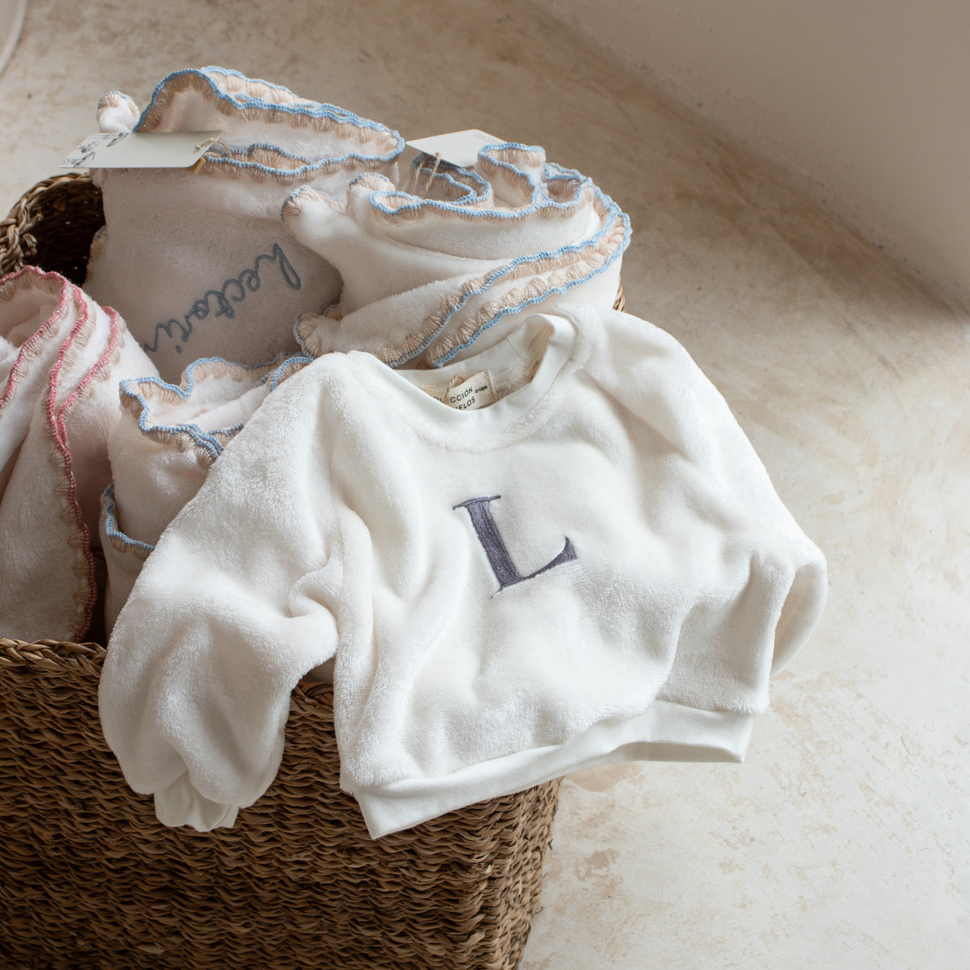 Sudadera polar para bebé con inicial bordada en gris sobre canasta