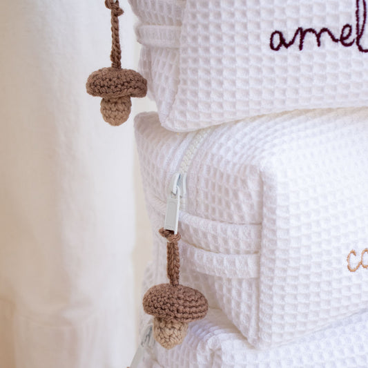 Detalle del neceser para bebé personalizado con textura de tela, cierre y accesorio tejido