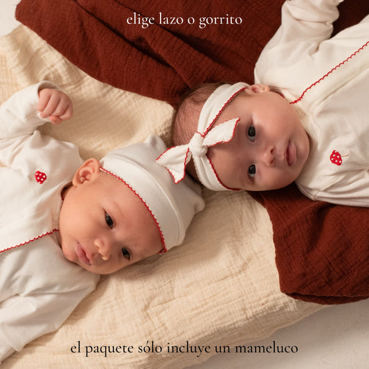 Bebés niño y niña usando el mameluco Alma y Nilo con gorrito y lazo, diseño unisex