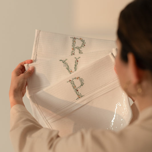 Bolsa transparente para bebé con inicial bordada mostrada en manos