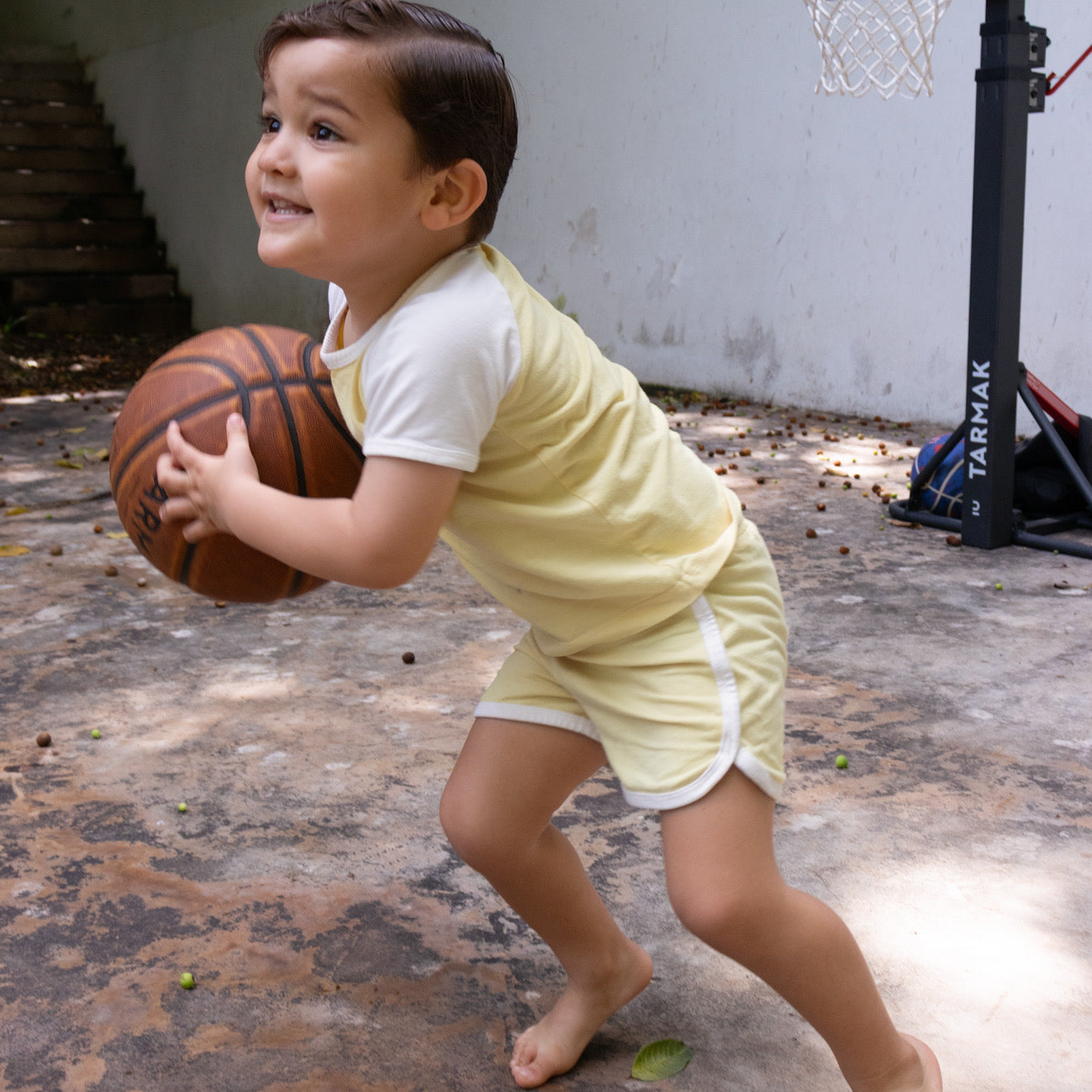 Conjunto deportivo unisex para niño en amarillo con mangas y bies marfil en uso jugando básquetbol