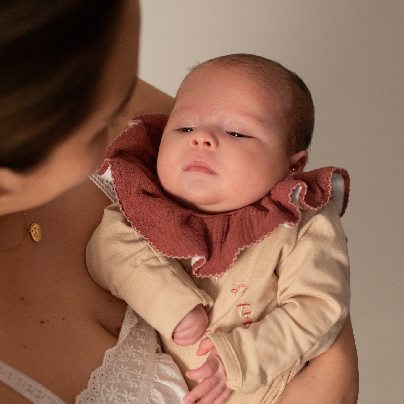 Cuello babero de muselina para bebé en color ladrillo en uso