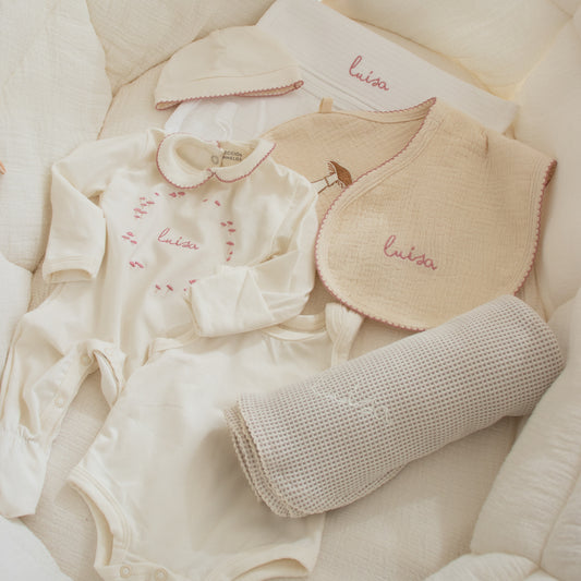 Piezas del set de bienvenida para bebé personalizadas, con mameluco en tonos rosas y marfil