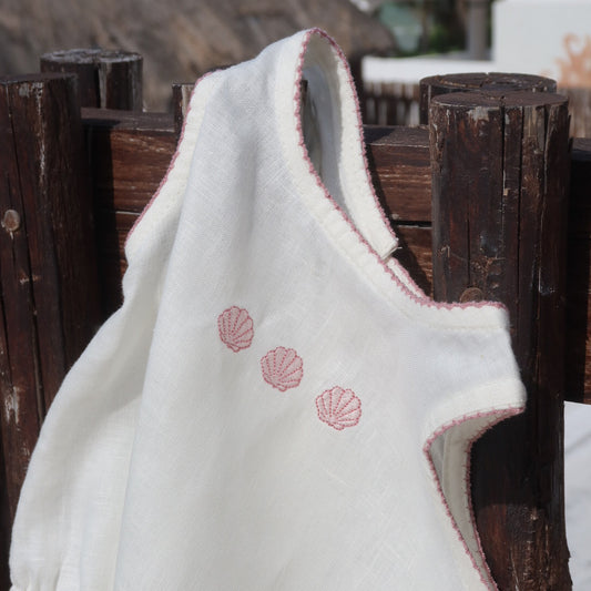 Detalle de pañalero de lino para bebé en color marfil con bordado de conchitas rosas