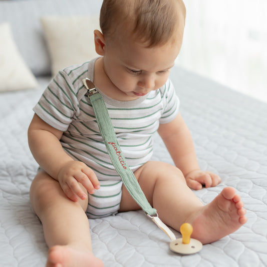 Bebé sentado con portachupón personalizado sujeto a la ropa