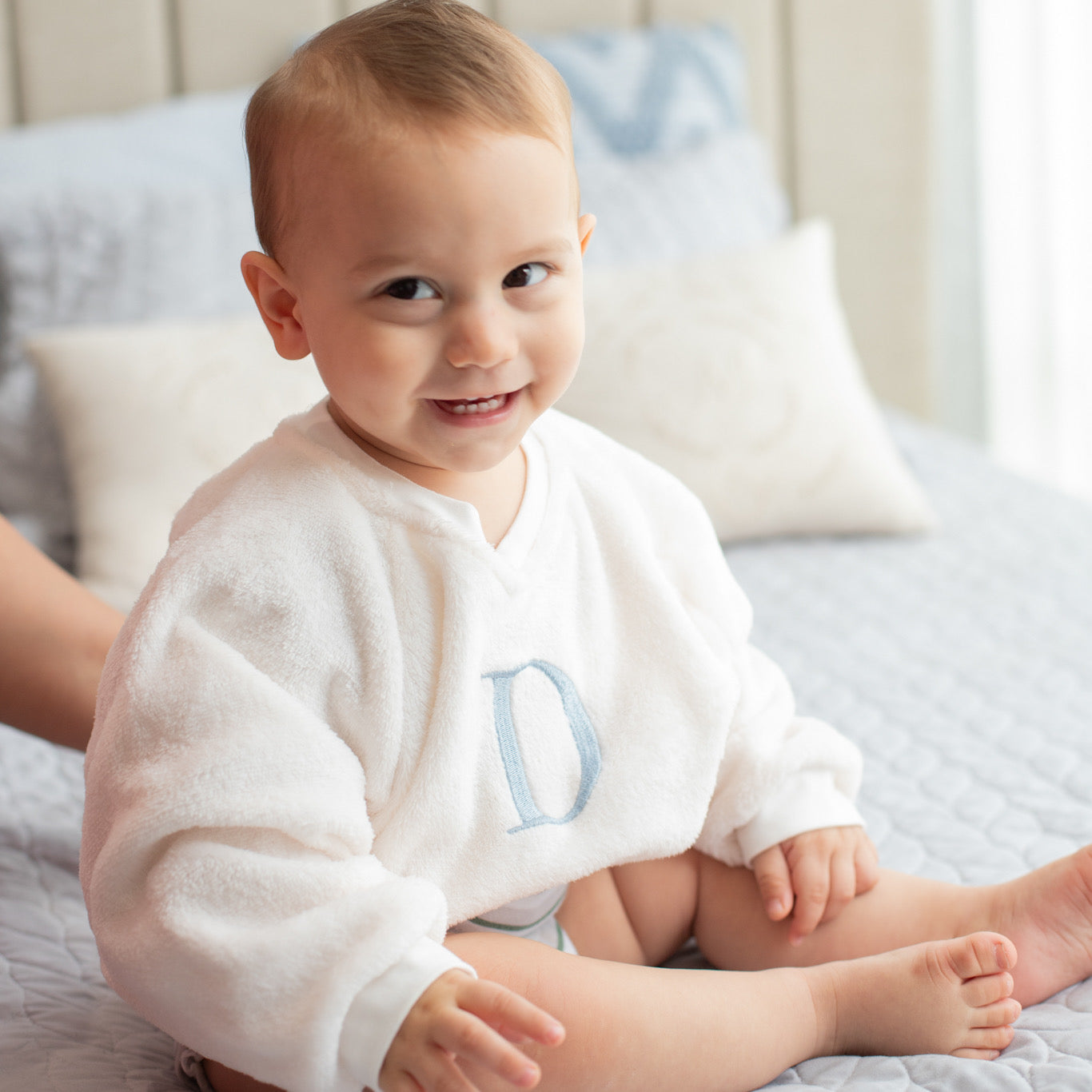 Bebé de un año con sudadera polar personalizada con inicial azul sentado
