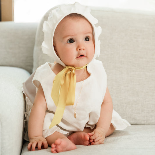 Bebé con vestido de lino para bebé celebración con gorrito y listón en uso
